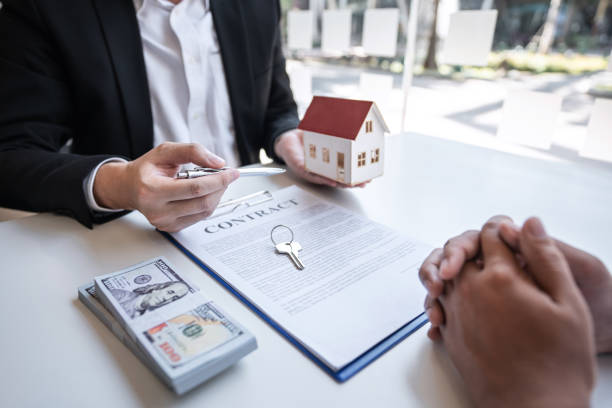 Real estate agent are presenting home loan and giving house, keys to customer after signing contract to buy house with approved property application form.