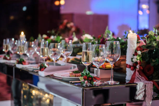 Wedding reception banquet party table. Wine glasses decorated with red peonies and roses. Forks and knives