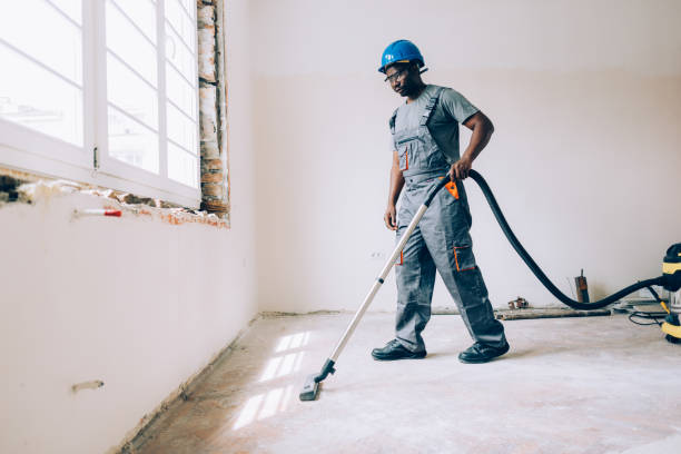An African American construction worker vacuuming the floors while renovating an apartment.
